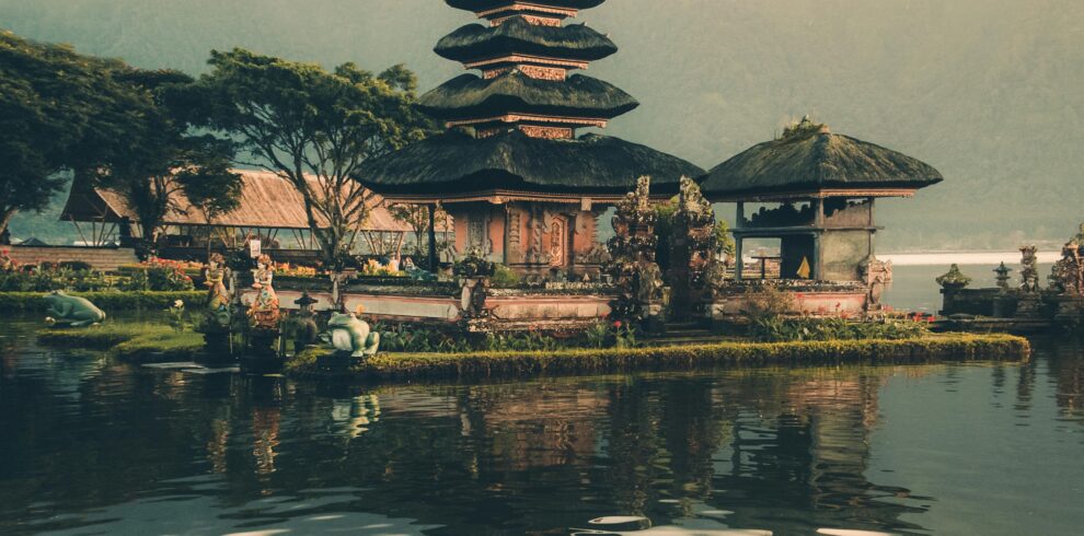 A serene view of Ulun Danu Beratan Temple with reflections on the water at sunrise, Bali.